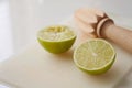 Wooden squeezer and lime cut on half on a table on a white plastic cutting board Royalty Free Stock Photo