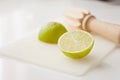 Wooden squeezer and lime cut on half on a table on a white plastic cutting board Royalty Free Stock Photo