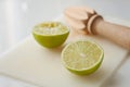 Wooden squeezer and lime cut on half on a table on a white plastic cutting board Royalty Free Stock Photo