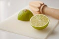 Wooden squeezer and lime cut on half on a table on a white plastic cutting board Royalty Free Stock Photo
