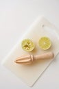 Wooden squeezer and lime cut on half on a table on a white plastic cutting board Royalty Free Stock Photo