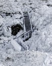 Wooden staircase frozen in ice, covered with icicles against a frozen lava field covered with ice and snow Royalty Free Stock Photo