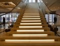 Wooden staircase with illuminated steps and glass railing Royalty Free Stock Photo