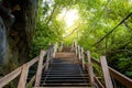 Wooden staircase leads up the mountain towards the sunlight on forest green natural and stone cave It is a beautiful natural Royalty Free Stock Photo