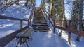 A wooden staircase with a railing rises to a snow-covered hill. Royalty Free Stock Photo