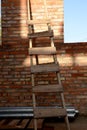 A wooden staircase rests on a brick wall inside a building under construction. Construction concept Royalty Free Stock Photo