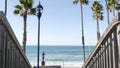 Wooden stairs, beach access in California USA. Coastal stairway, pacific ocean waves and palm trees.