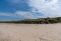 Wooden stairs lead over tall grassy sand dunes onto an empty picturesque golden sand beach Royalty Free Stock Photo