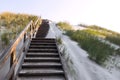 Wooden stairs on sand dune covered with grass, way to the entrance of the beach. Coastal landscape by morning light. Baltic sea