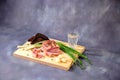 Wooden stand with a glass of Russian vodka, a piece of lard, green onions, pepper, garlic and slices of rye bread on a gray