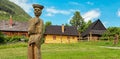 Wooden statue of villager in front of picturesque historical village Vlkolinec witjh wooden colorful cottages in Slovakia