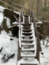 Wooden steps near the cliff. Staircase made of wood in the snow. Wooden structure for climbing the mountain Royalty Free Stock Photo