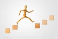 Wooden stick figure jumping from one wooden block on rising steps to the next - achievement, career or objective concept on white Royalty Free Stock Photo