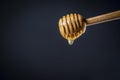 Wooden stick for honey with drop honey. Thick honey dripping and flowing down from the honey spoon on black background, close up Royalty Free Stock Photo