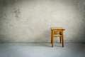 Wooden stool in empty room. Chair on cement floor. Grunge interior
