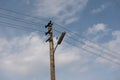 Wooden street lamp post with electric wires against blue sky with white clouds Royalty Free Stock Photo