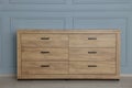 Wooden stylish chest of drawers near grey wall indoors
