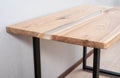 Wooden stylish table made of solid wood with epoxy resin on the background of the floor and wall. Close-up