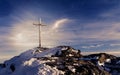 Wooden summit cross on the mountain peak with cloudy clear sky
