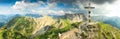 Wooden summit cross and summer colors in mountains. Panoramic view.