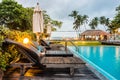 Wooden sunbeds and parasols on wooden deck nearby swimming pool Royalty Free Stock Photo