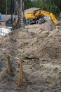 Wooden supports on the construction site. In the background backhoe digging the ground for the foundation.