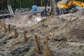 Wooden supports on the construction site. In the background backhoe digging the ground for the foundation.