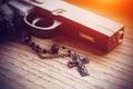 On the wooden surface lies a black gun and a black cross on a chain Royalty Free Stock Photo