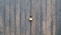 Wooden surface of old textured brown planks closed on a rusted lock close up. Old wooden gate with a metal lock. brown