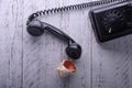 On a wooden surface with white shabby paint, a vintage black telephone, a beautiful sea shell lies next to the handset.