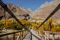 Wooden suspension bridge leads to Khalti village in autumn season against Hindu Kush mountain range Royalty Free Stock Photo