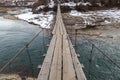 Wooden suspension bridge over a mountain river in a mountain village Royalty Free Stock Photo