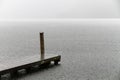 Wooden swimming platform as bridge docking pier deck on an alpine lake during heavy rain with nobody