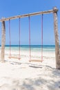 Wooden swing on the beach. Swing with two seats on scenic seascape. Idyllic exotic resort. Tropical paradise. Empty swing.