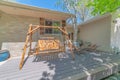 Wooden swing bench at the backyard deck of a house viewed on a sunny day