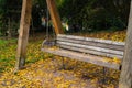 Wooden swing chair with yellow leaves on the ground in autumn park. Royalty Free Stock Photo