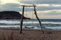 Wooden swing on an empty beach during the romantic sundown