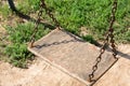 Wooden swing hanging from chains in the yard Royalty Free Stock Photo