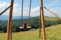 Wooden Swing on Mountain Meadow: A Serene Retreat with Majestic Mountain View and Lush Pine Forest. Enjoy a Sunny Summer Day as a