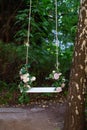 Wooden swing in playground outdoors. Empty swing placed in park. Wedding swing decorated with flowers roses. Garden swing hanging Royalty Free Stock Photo