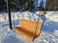 Wooden swings on chains hang in the park on a winter snowy day