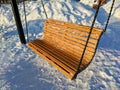 Wooden swings on chains hang in the park on a winter snowy day. Close-up