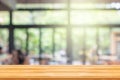 Wooden table with abstract blurry image of coffee shop or cafe restaurant in background for product showing and advertising.