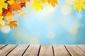 Wooden table against blurred autumn leaves on blue bokeh background Royalty Free Stock Photo