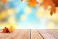 Wooden table with autumn leaves on bokeh light blue, white and yellow background. Royalty Free Stock Photo