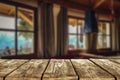 Wooden table background with dark interior and windows.