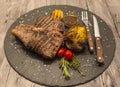 On wooden table background juicy beef steak medium rare on a stone baked potatoes and barbecue sauce and large sea salt with fork Royalty Free Stock Photo