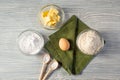 On a wooden table: baking ingredients, green napkin, wooden spoons, baking soda, dry yeast