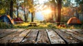 A wooden table with a beautiful blurred background of a campsite in the woods with a warm sunlight shining through the trees