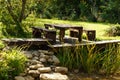 Wooden table bench in garden with stones and green fields Royalty Free Stock Photo